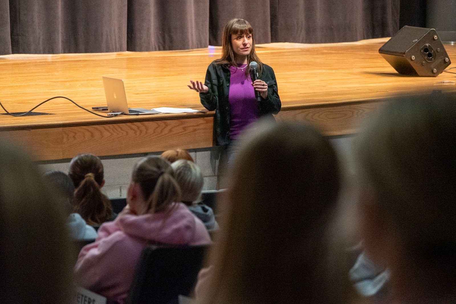 Cyd Gottlieb stands in front of a stage while presenting.